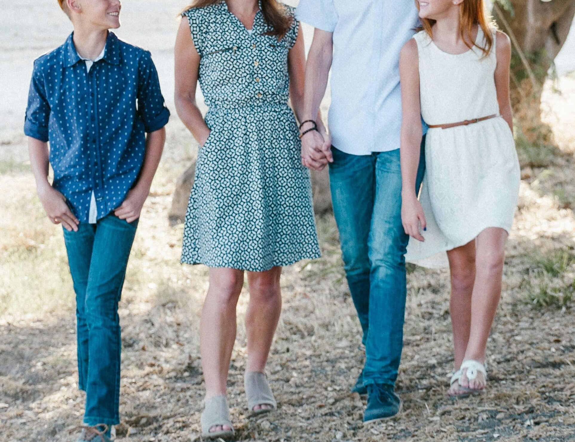 Image of a happy family holding hands and walking outside. Work closely with a skilled family therapist to help your family cope with conflict and communicate in healthy ways in family therapy in Englewood, CO.