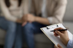 A close up of a person taking notes while sitting across from a couple. Learn how couples therapy in Greenwood Village, CO can offer support by contacting a relationship therapist in Englewood, CO. Search for couples therapy in Littleton, CO and other services today. 